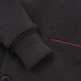 Close-up of a dark gray sweater with buttons and a red detail on the pocket.