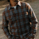 Man wearing a brown plaid shirt with a blurred background