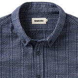 Close up of buttoned-down collar on blue grid-patterned button up shirt