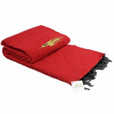 Red blanket with black tassels and a yellow emblem on a white background