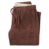 Textured red brick colored pants with a drawstring folded on a flat white background.