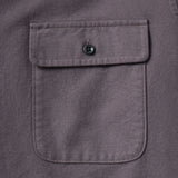 Closeup of chest pocket on a purple shirt with a flap secured by a small black button