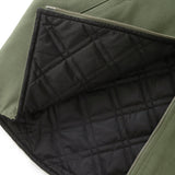 Close up of bottom section of an olive green canvas vest, partially unzipped to show black quilted interior lining.