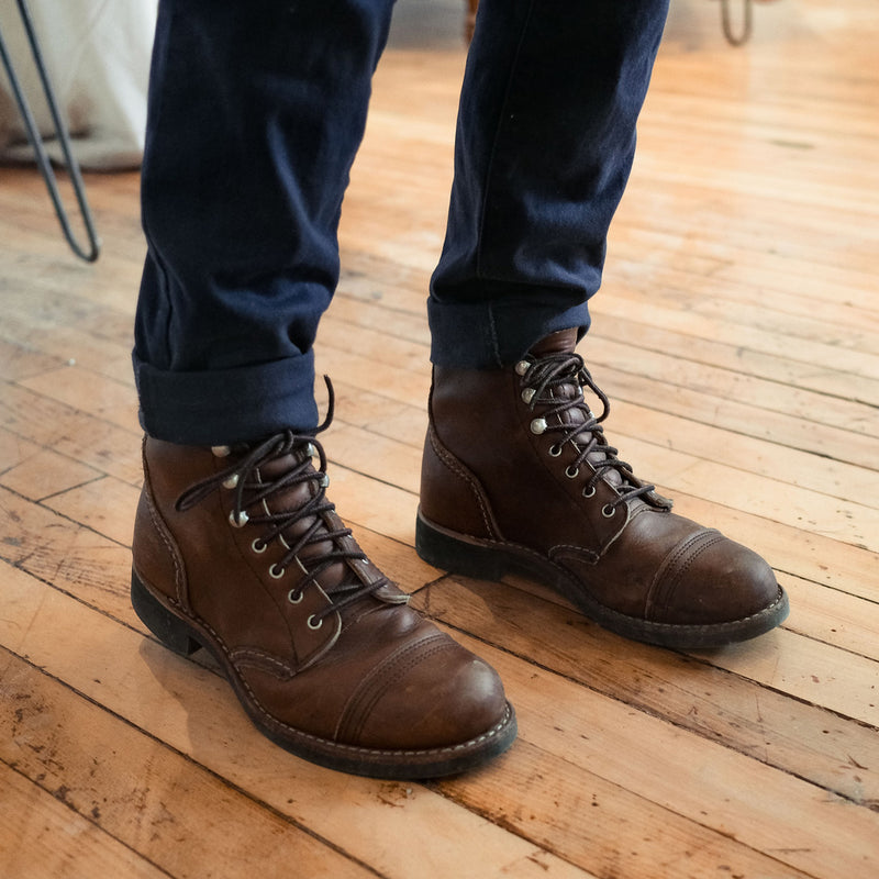 Person wearing iron ranger boots standing on hard wood floor