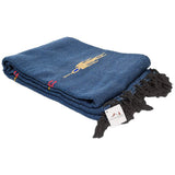 Folded blue blanket with tassels and embroidery on a white background