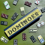 Dominoes set with pieces scattered around on a green surface