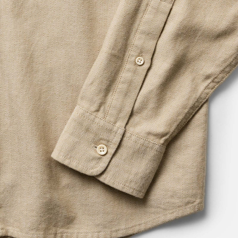 Close-up of a beige shirt with rolled-up sleeve on a light gray background