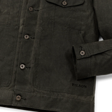Close up of dark gray waxed canvas trucker-style jacket with metal buttons going down the center and button-secured sleeves. The text [Filson] is embroidered in dark gray toward the bottom of the wearer's right hand pocket above the bottom hem