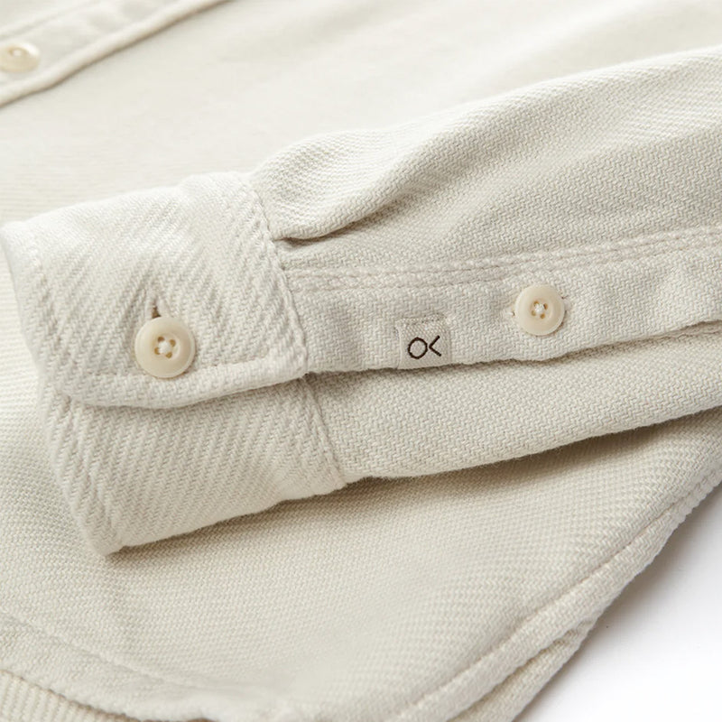 close up cuff and small logo tag of the outerknown blanket shirt in white ecru with white buttons