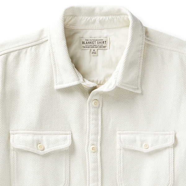 close up collar and tag and front flap pockets of the outerknown blanket shirt in white ecru with white buttons