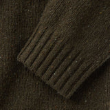 Close up of ribbed cuff of dark olive knit sweater with small flecks of color woven in. 