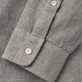 Close up of buttoned cuff of gray waffle-texture shirt