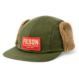 Front angled view of olive green cap with fleece flaps snapped to the side. There is a red cloth patch on the front with white text reading [FILSON Original Alaska Outfitter Since 1897]