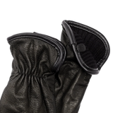 Close up of wrist of pair of black leather gloves so that the black wool lining is visible