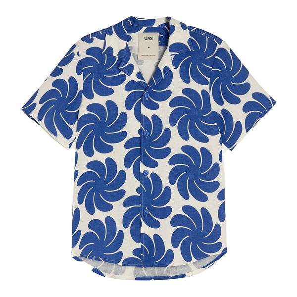 "blue cartoonish flower or palm leaves on a cream button up linen shirt"