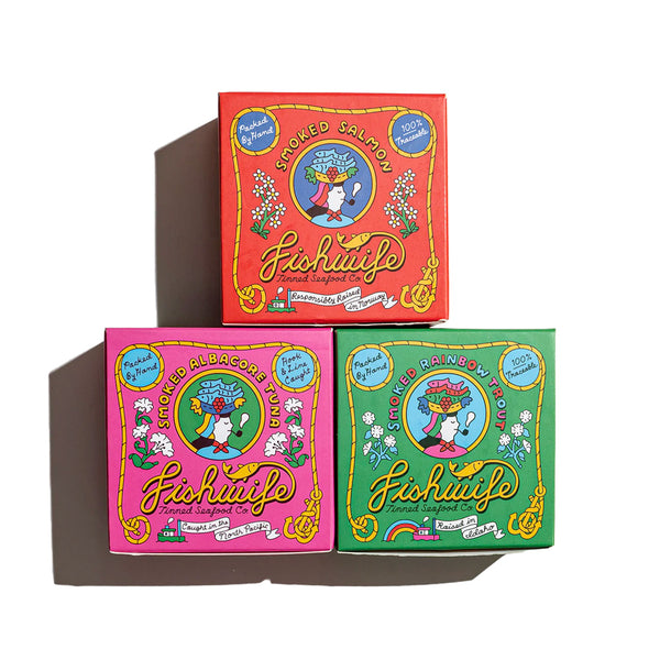 "three boxes containing different types of canned fish. salmon and albacore tuna and rainbow trout"