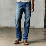 Man wearing medium shade, stone-washed indigo denim, white tee, and brown boots