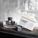 3 whisky stones in a whisky glass next to 3 whisky stones and the cardboard package