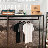 Three Blank Tees in Black, White and Grey Hanging from a Rack.