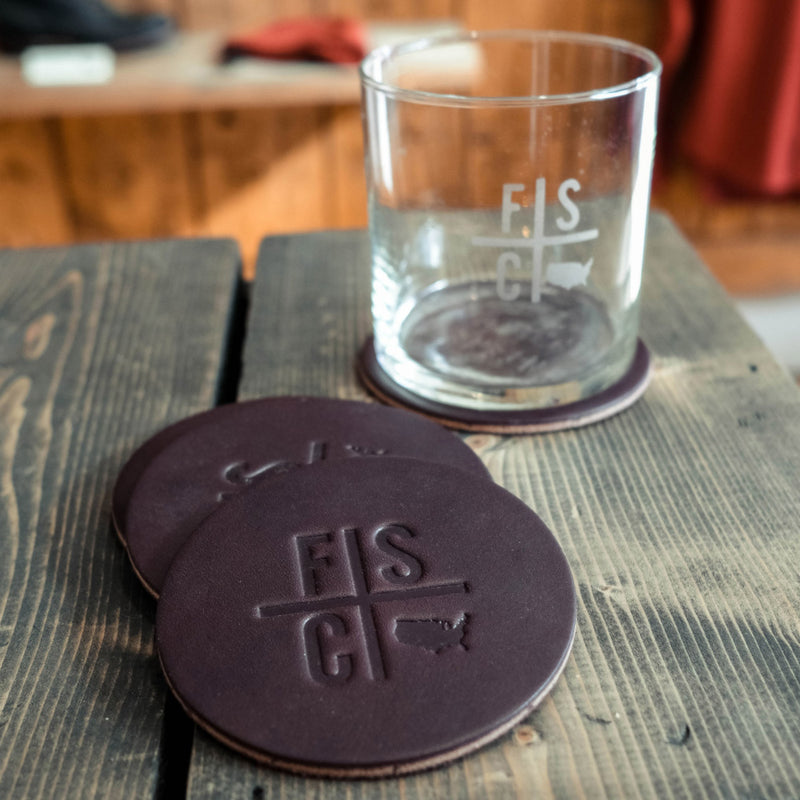 A whiskey glass on top of a leather coaster