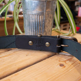 A Black Belt with Antique Brass Hardware with the Inside Showing.